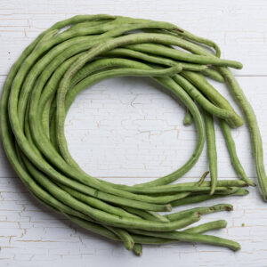 Snake Beans all curled up in a circle in a white wooden tabletop