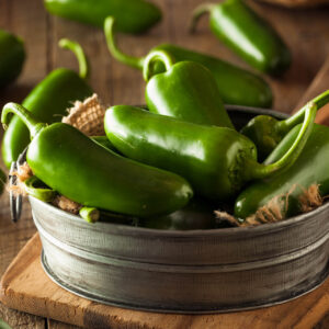 a metal bowl of jalapeno chilli on brown wooden table