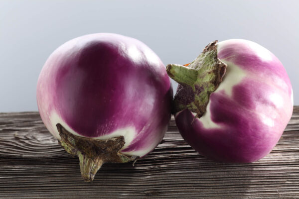 Two Rosa Bianca eggplants on a table with a lilac background