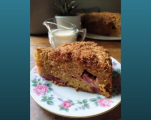 Rhubarb cake on a plate with a jug of cream