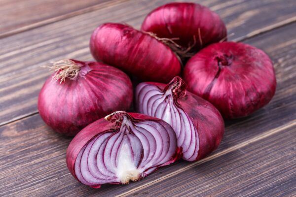 Group of Red Burgundy Onions sitting on a wooden bench.