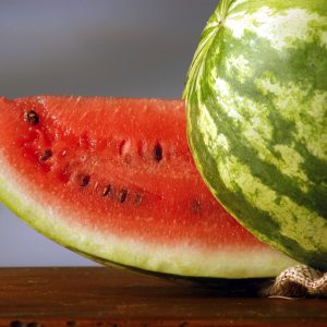 Large Slice of Bush Jubilee Watermelon next to the entire melon to show its red flesh